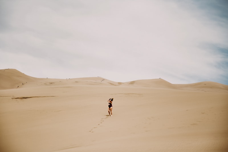 Maternity Photographer, woman walks in swimsuit in Sand Dunes
